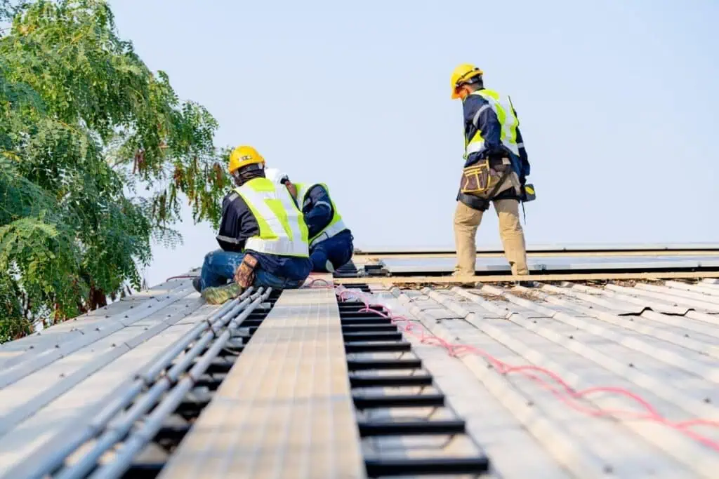 Roofing workers installing metal panels on a building roof.